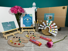 Load image into Gallery viewer, A gift set for couples date nights including easel stands, paint pallets, canvases, sketching pencils, paint brushes, a guide, and optional chocolates and teddies, all displayed with recyclable packaging.